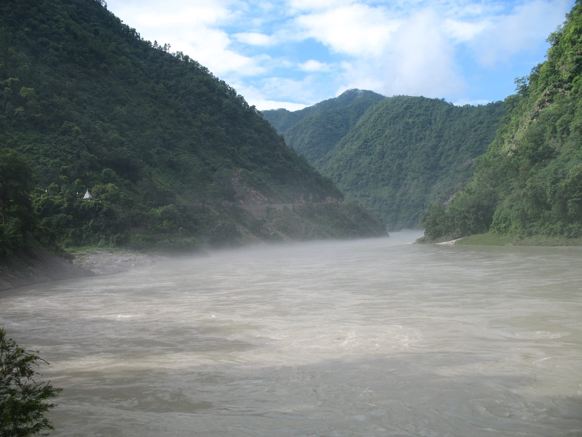 The Ganges rushing past forested banks on the rafting stretch near Shivpuri, above Rishikesh